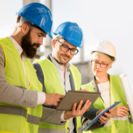 Three construction works looking over information at a jobsite